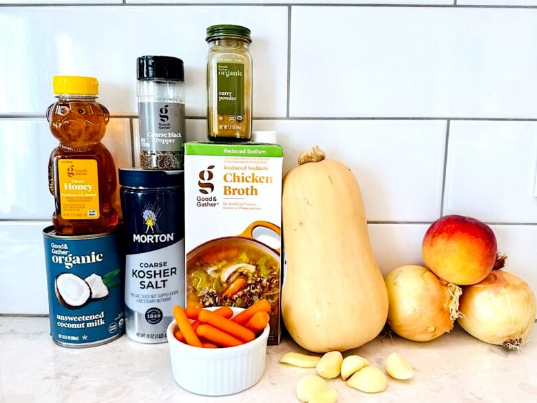 Ingredients to make curry butternut squash soup on a white kitchen counter.