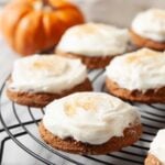 Closeup shot of pumpkin cookies with cream cheese frosting on a wire rack.