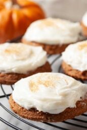 Closeup shot of pumpkin cookies with cream cheese frosting on a wire rack.