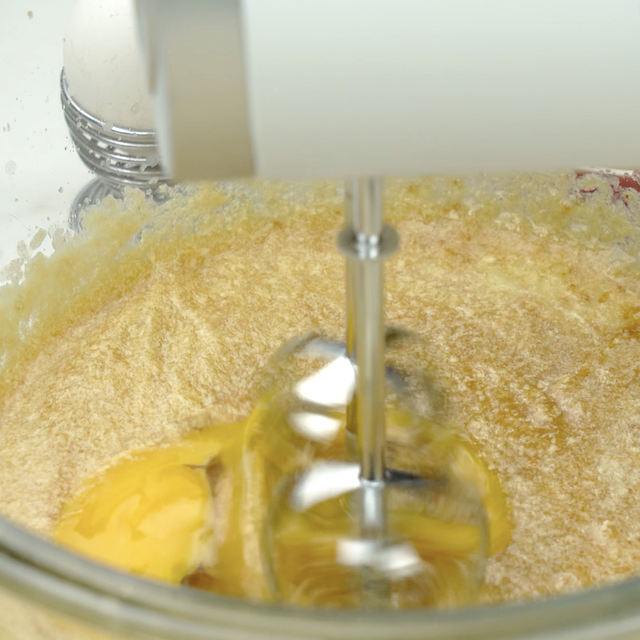 Eggs being beaten into butter-sugar mixture to make pumpkin donut holes at home.