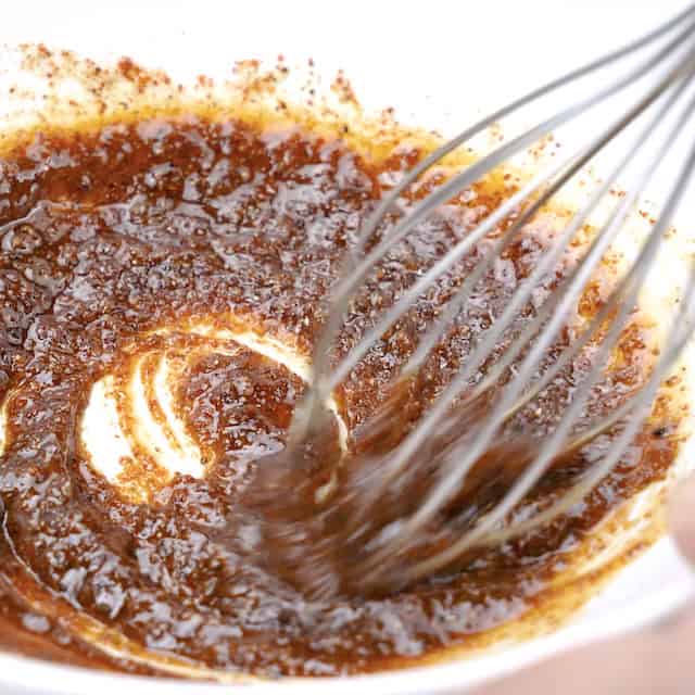 Spice and butter mixture being whisked together to make roasted cashews.