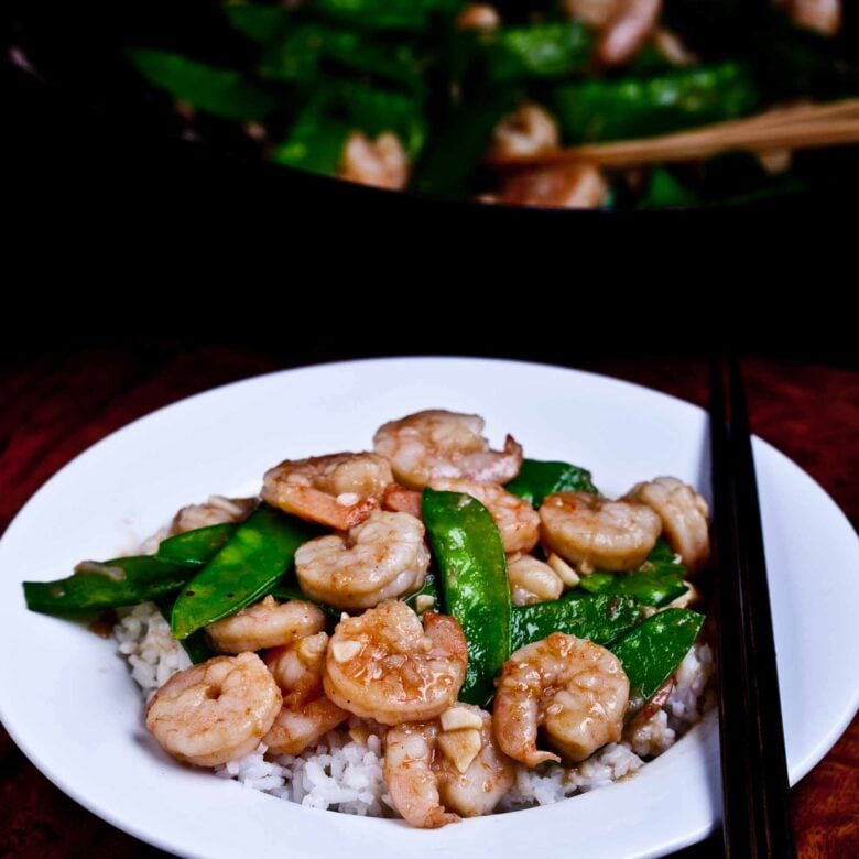 Homemade shrimp with snow peas in a plate, served over jasmine rice.
