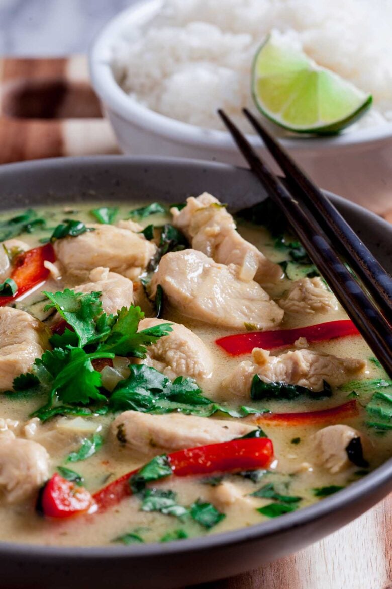 Closeup shot of a bowl with thai chicken curry, with chopsticks on the side.