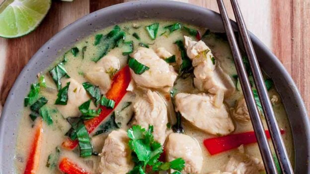 Overhead shot of a bowl with thai chicken curry, with chopsticks on the side.
