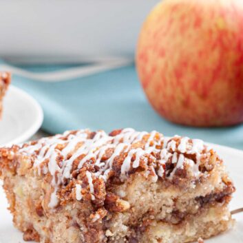 Closeup shot of a slice of apple coffee cake with pecan streusel topping and icing.