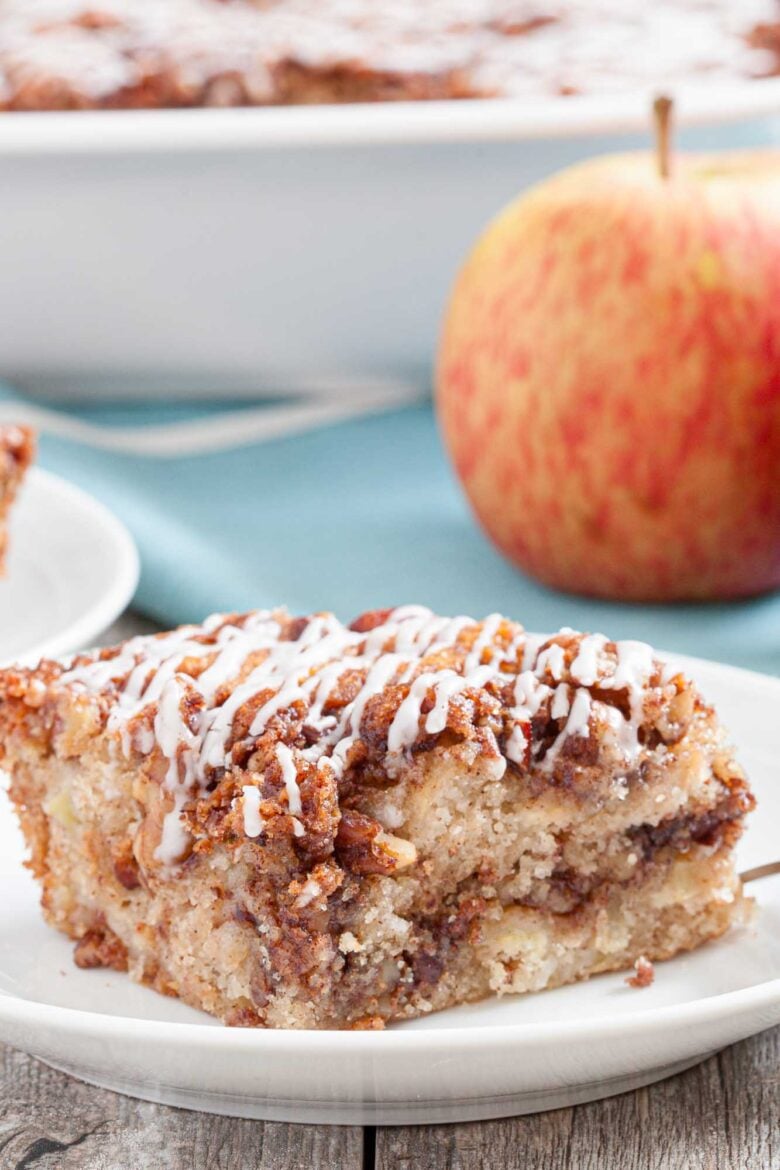 Closeup shot of a slice of apple coffee cake with pecan streusel topping and icing.