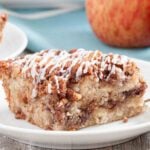 Closeup shot of a slice of apple coffee cake with pecan streusel topping and icing.