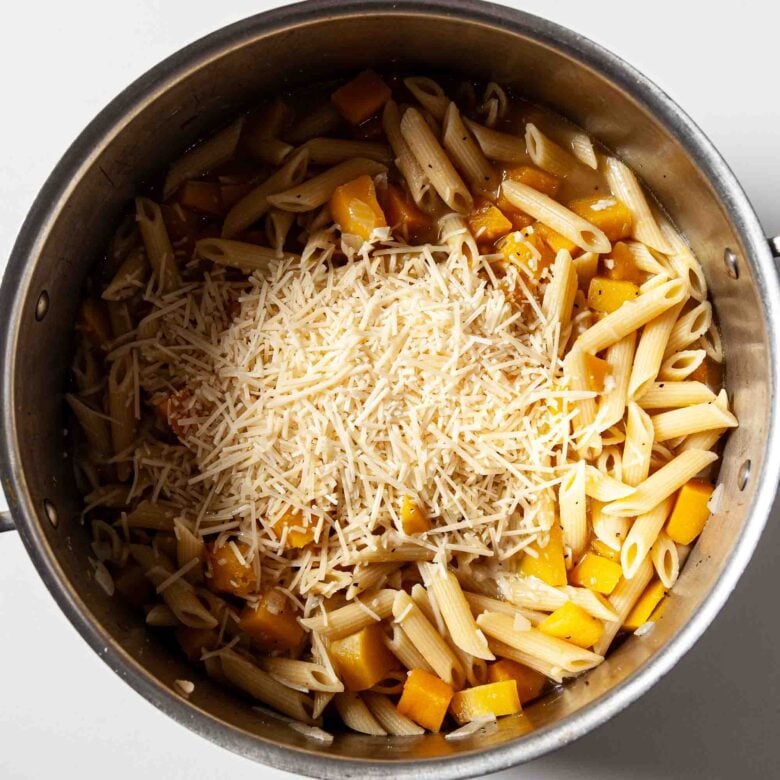 Parmesan cheese being added to make butternut squash pasta at home.