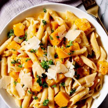 Overhead shot of a bowl with homemade butternut squash pasta with a fork on the side.