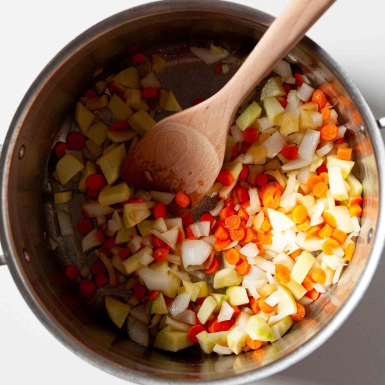 Aromatics being sautéed in a pot to make curry butternut squash soup.