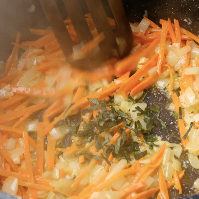 Carrots, onions, garlic and herbs being sauteed.
