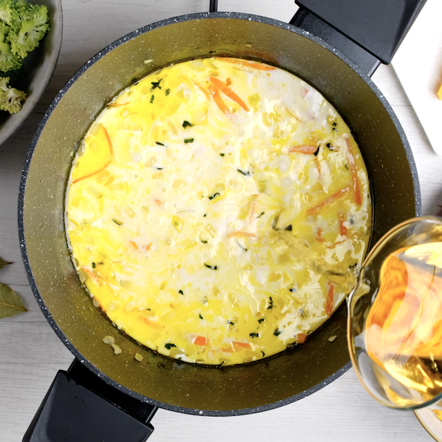 Broth being added to pot to make broccoli cheese soup at home.