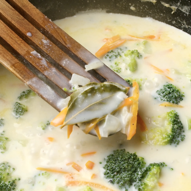 Bay leaf being removed from pot to make broccoli cheese soup.