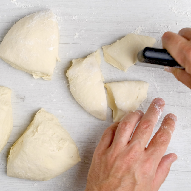 Olive garden breadstick dough being cut into pieces.