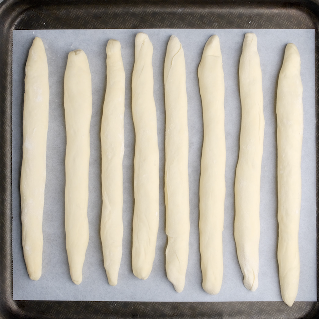 Breadstick logs on a parchment lined baking sheet.