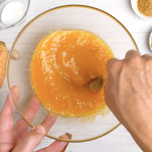 Wet ingredients being whisked into mashed sweet potatoes.