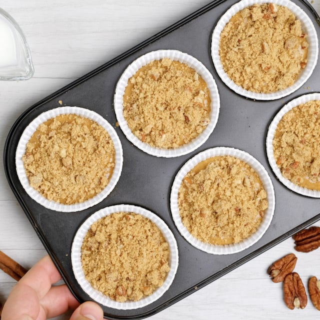 Sweet potato muffin batter with topping in muffin tin, ready to be baked.