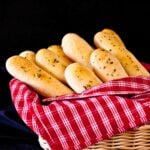 Homemade Olive Garden copycat breadsticks in a basket with a red striped towel.