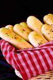 Homemade Olive Garden copycat breadsticks in a basket with a red striped towel.