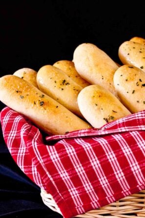 Homemade Olive Garden copycat breadsticks in a basket with a red striped towel.