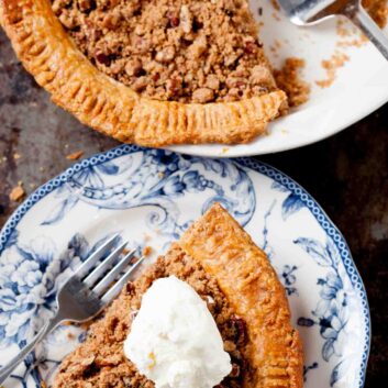 Overhead shot of sweet potato pecan pie slice on a blue pattern plate, with more on the side.