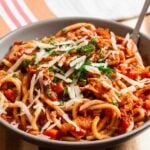 Closeup shot of turkey bolognese topped with chopped parsley and shaved parmesan.