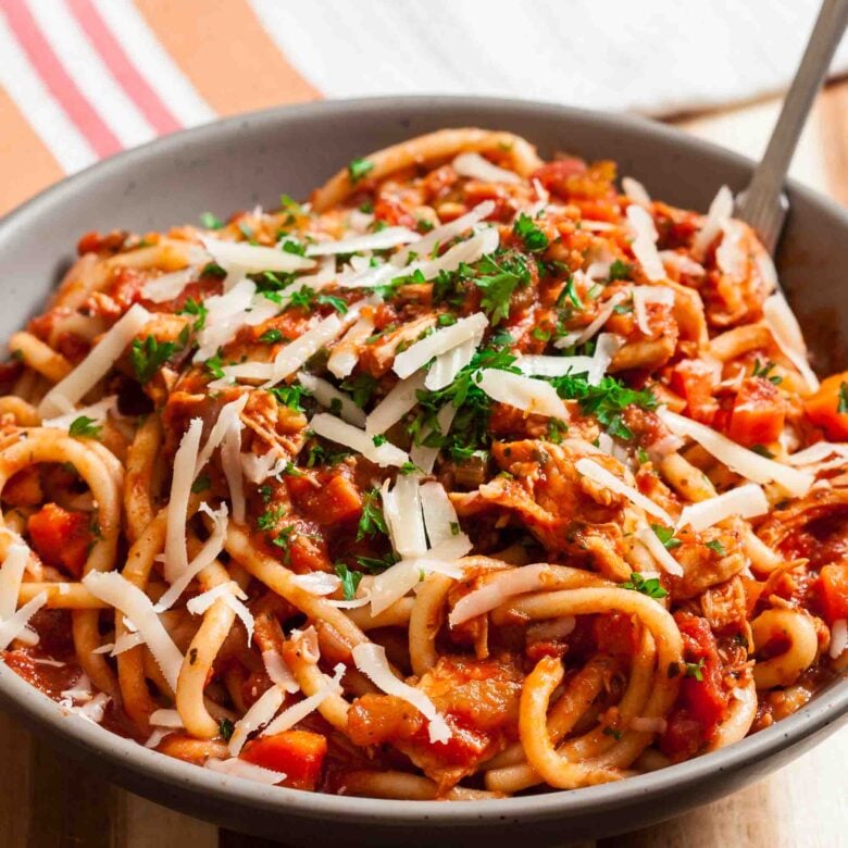 Closeup shot of turkey bolognese topped with chopped parsley and shaved parmesan.