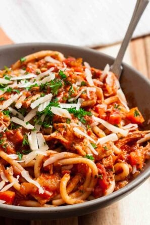 Closeup shot of turkey bolognese topped with chopped parsley and shaved parmesan.