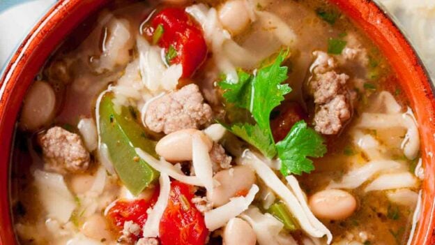 Overhead shot of a bowl with white bean turkey chili with lime wedges on the side.