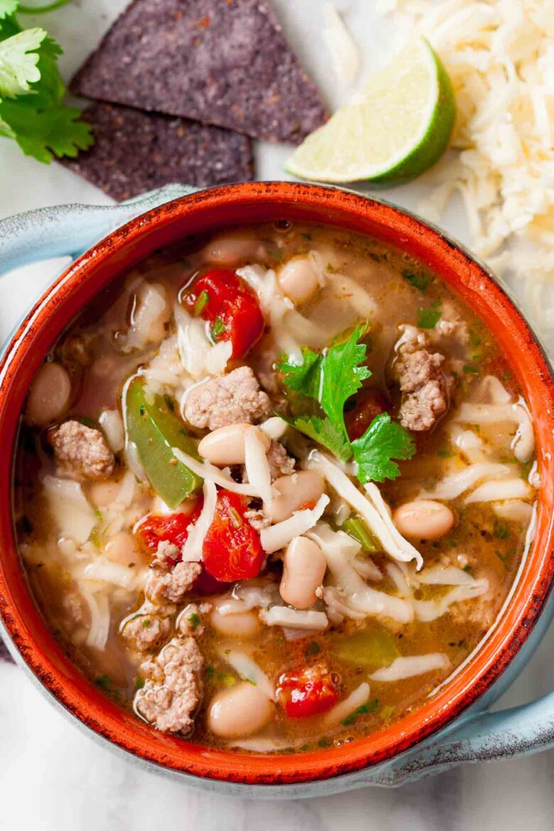 Overhead shot of a bowl with white bean turkey chili with lime wedges on the side.