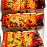 Overhead shot of Asian baked salmon fillets with chopped green onions on top.