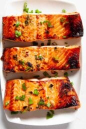 Overhead shot of Asian baked salmon fillets with chopped green onions on top.
