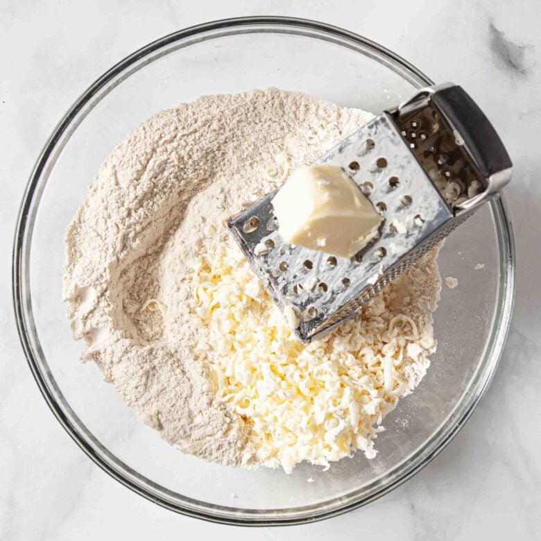 Cold butter being grated into flour to make scones.