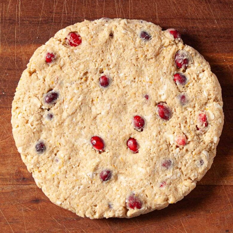 Cranberry orange scone dough rolled out into a round.