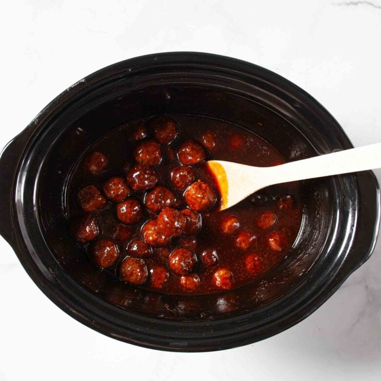 Grape jelly meatballs and ingredients in a slow cooker.