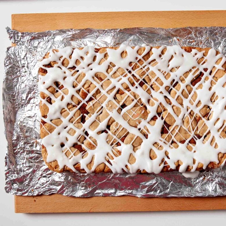 Snickerdoodle cookie bar topped with drizzle, ready to be cut into squares.