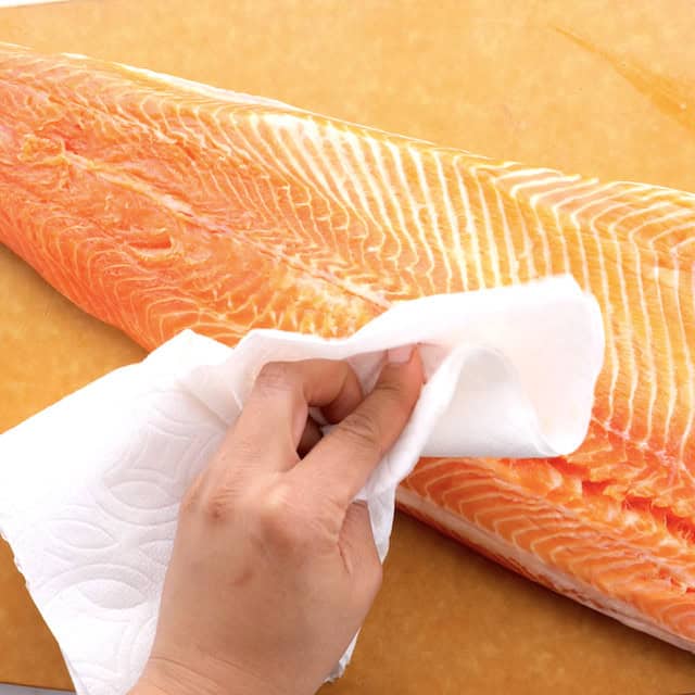 Salmon being patted dry to make asian baked salmon.