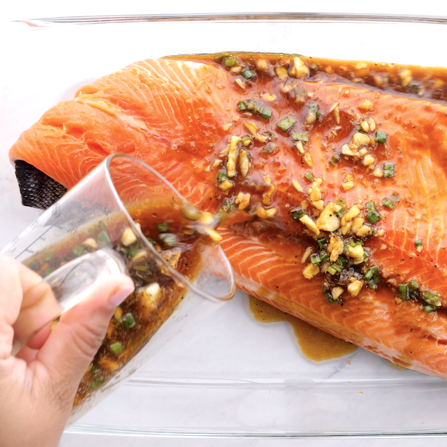 Marinade being poured over salmon.