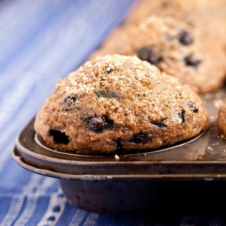 Closeup shot of blueberry steel cut oat muffins in a baking pan with visible blueberries.