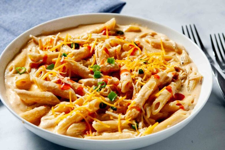 A bowl with a serving of buffalo chicken pasta with fork on the side.