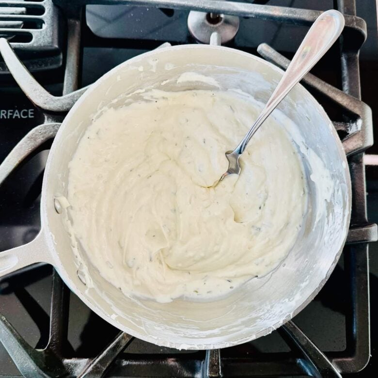 Cream cheese being warmed in a pot to make buffalo chicken pasta.