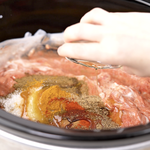 Spices being added to a slow cooker to make chicken tikka masala.