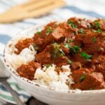 Closeup shot of a plate with slow cooker chicken tikka masala served over rice.