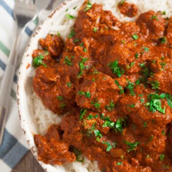 Overhead shot of slow cooker chicken tikka masala with a spoon and fork on the side.