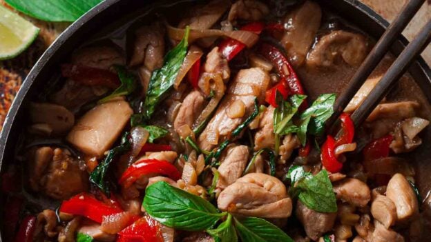 Overhead shot of a pan with thai basil chicken and chopsticks on the side.