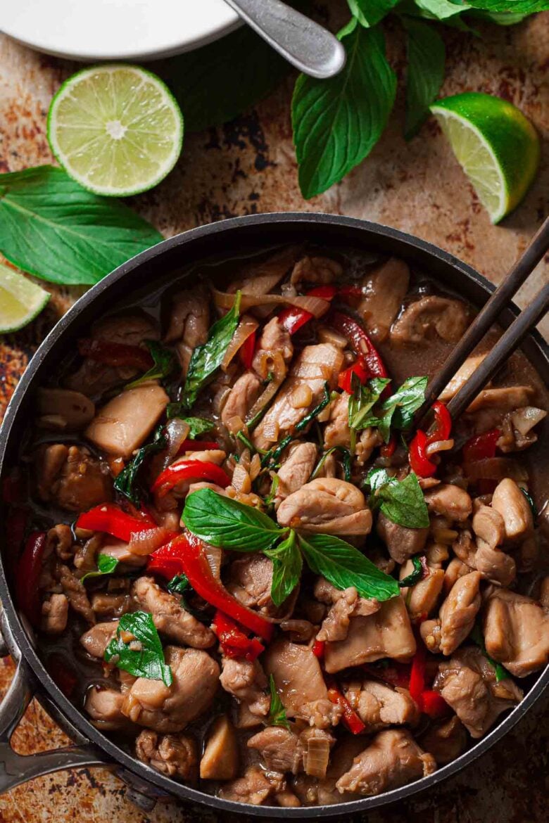 Overhead shot of a pan with thai basil chicken and chopsticks on the side.