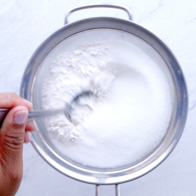 Cake and sugar being sifted into a bowl.