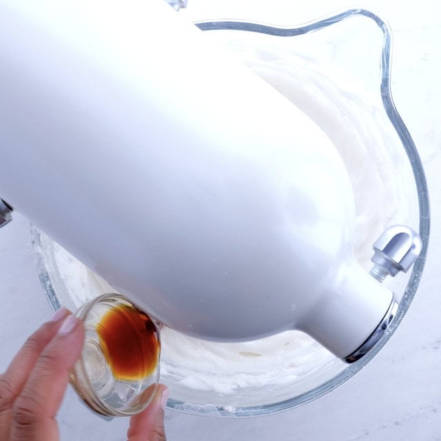 Vanilla extract being poured into stand mixer to make angel food cake recipe.