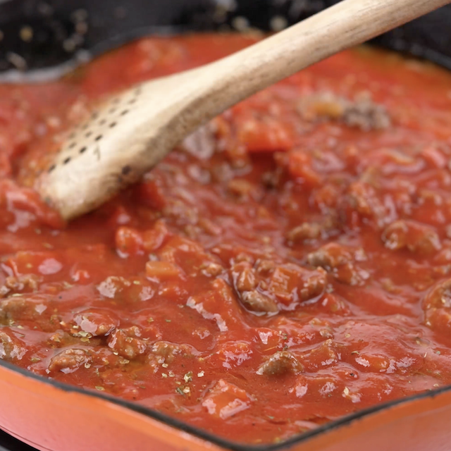 Pasta sauce being added to a pan.