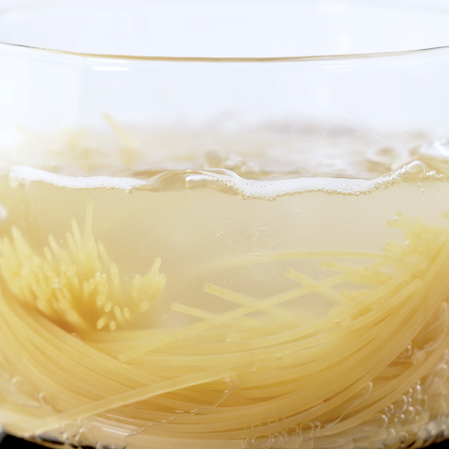 Pasta being boiled in a glass pot.